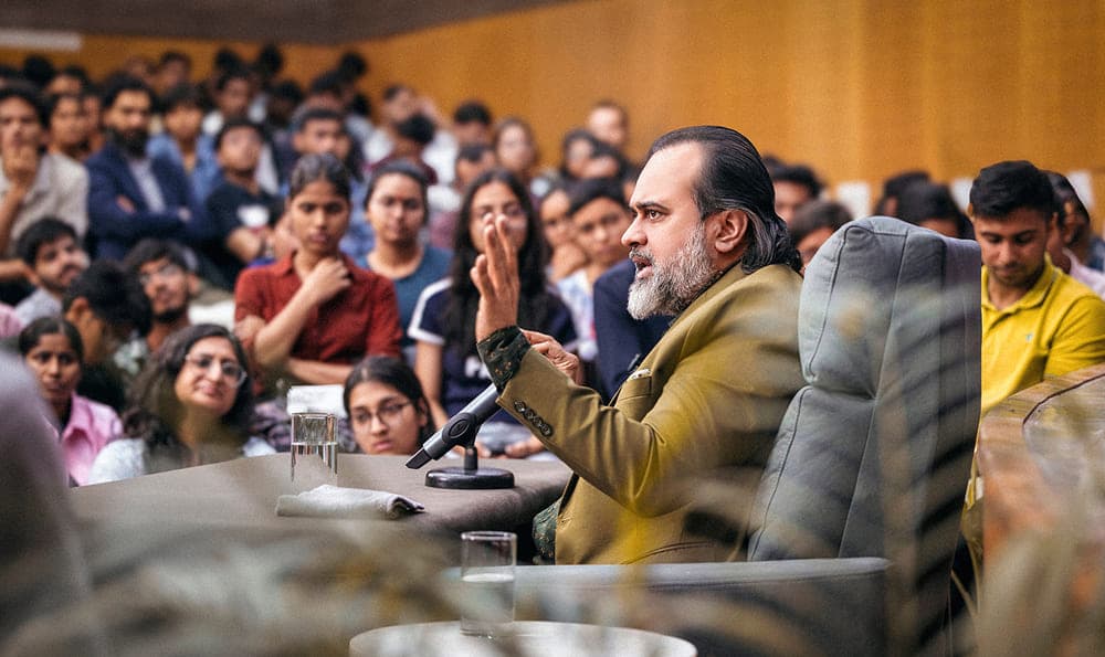 Acharya Prashant sitting on stage with students answering questions