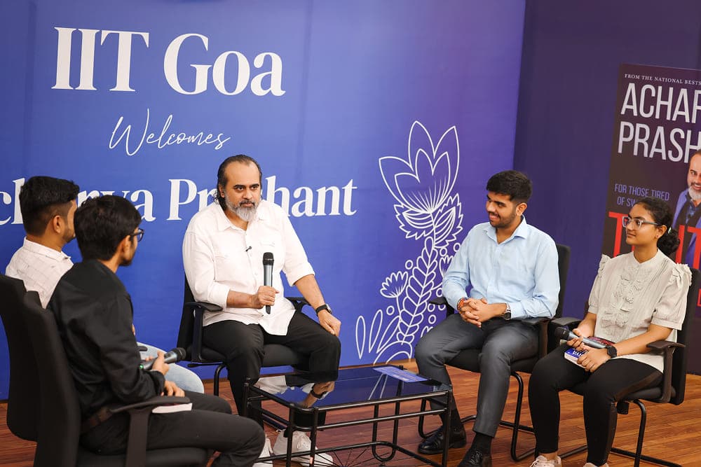 Acharya Prashant sitting on stage with students answering questions
