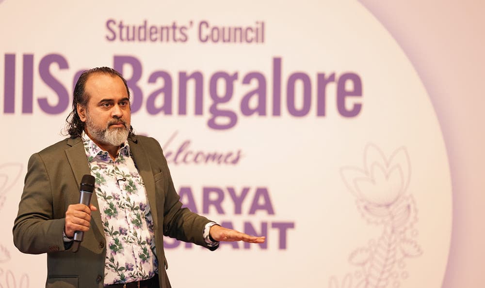 Acharya Prashant sitting on stage with students answering questions
