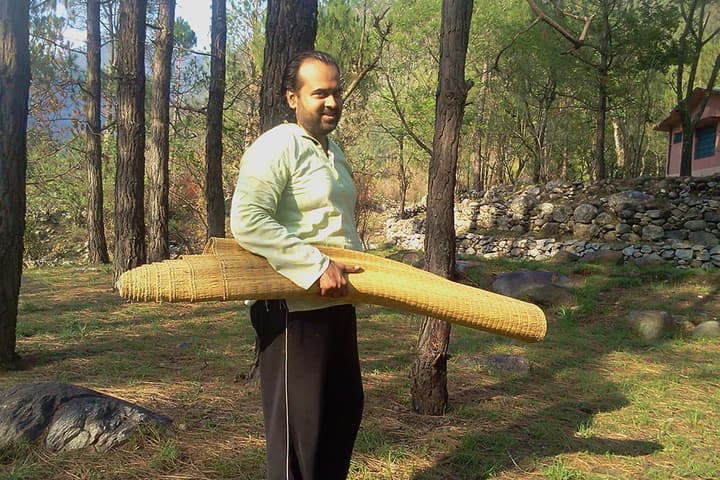 Acharya Prasant in mountains, holding a mat in his hands.