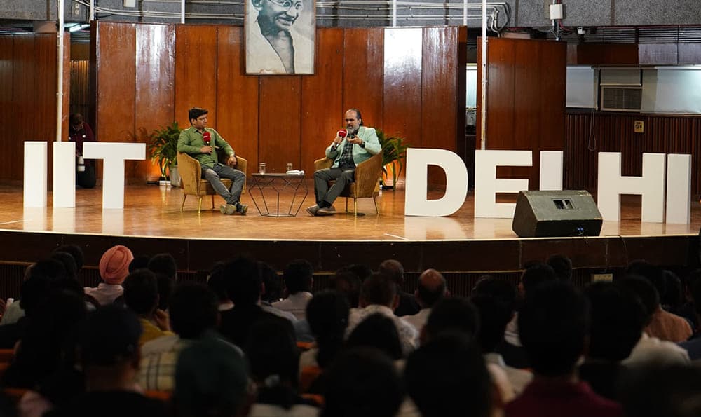 Acharya Prashant sitting on stage with students answering questions